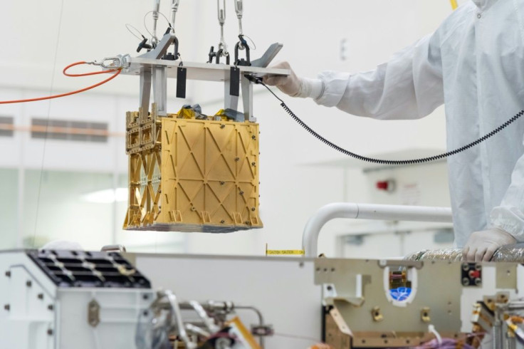 This handout photo obtained April 21, 2021 and released by NASA/JPL shows technicians in the clean room carefully lowering the Mars Oxygen In-Situ Resource Utilization Experiment (MOXIE) instrument into the belly of the Perseverance rover