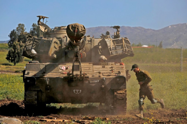 An Israeli soldier runs past an M109 howitzer mobile artillery cannon at a position near Moshav Sha'al in the Israeli-annexed Golan Heights on April 22, 2021
