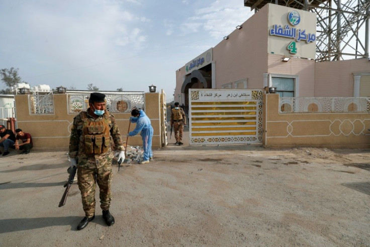 Iraqi policemen stand at the gate of Baghdad's Ibn al-Khatib hospital, which was ravaged by a fire that killed at least 82