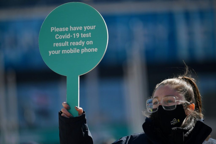 A worker holds a sign asking fans to prepare to show their negative test result for Covid-19, as they arrive at Wembley Stadium to watch the English League Cup final football match between Manchester City and Tottenham Hotspur