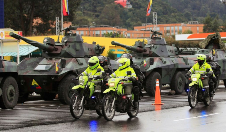 Riot police officers ride past army tanks on the outskirts of Bogota on May 4, 2021