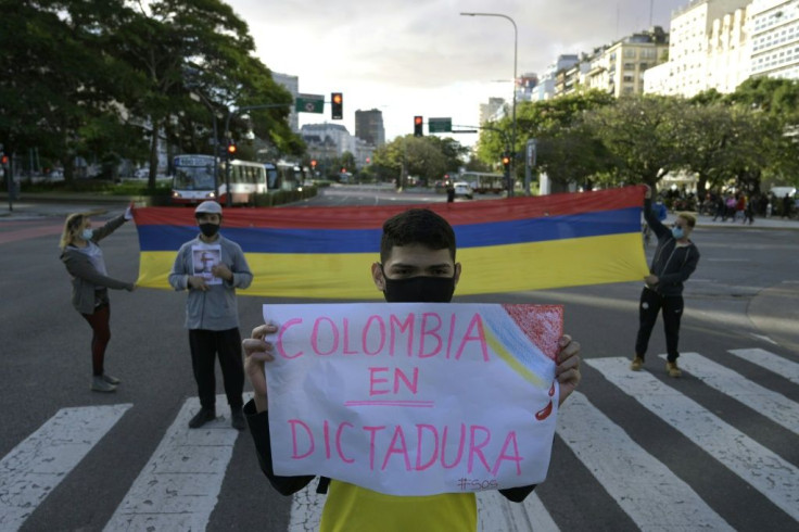 Colombians stand in front of their country's consulate in Buenos Aires, Argentina and hold up a sign reading, "Colombia is under dictatorship" during a demonstration against the Colombian government