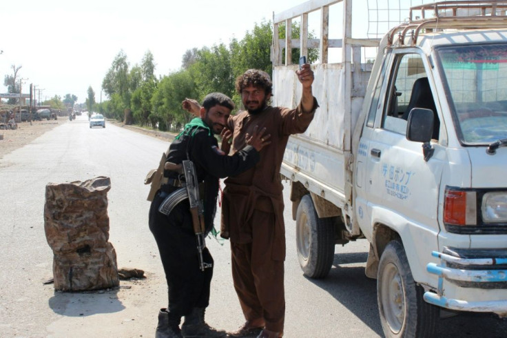 An Afghan policeman searches a man at a road checkpoint during the ongoing fighting between Afghan security forces and Taliban fighters, on the outskirts of Lashkar Gah