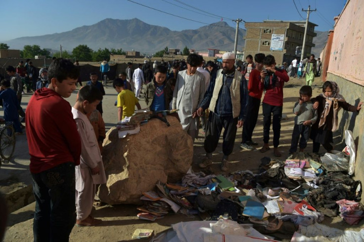 Onlookers stand next to a pile of backpacks and books of victims following multiple blasts outside a girls' school in Dasht-e-Barchi on the outskirts of Kabul