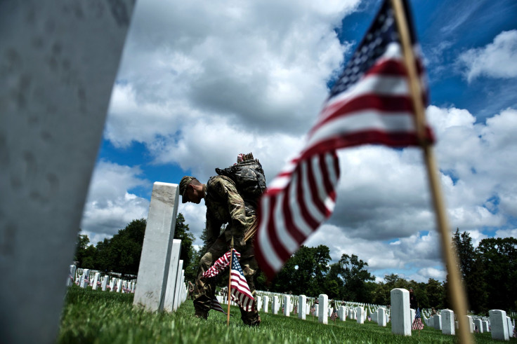 A soldier in the Old Guard places flags at graves in Arlington National Cemetery during 'Flags In' in preparation for Memorial Day in Arlington, Virginia, May 25, 2017.