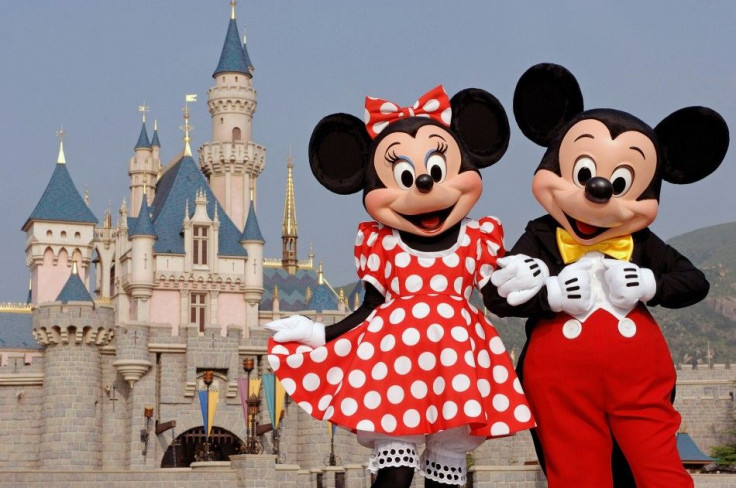 Disney characters Mickey Mouse and Minnie Mouse pose in front of the Sleeping Beauty Castle in Hong Kong.
