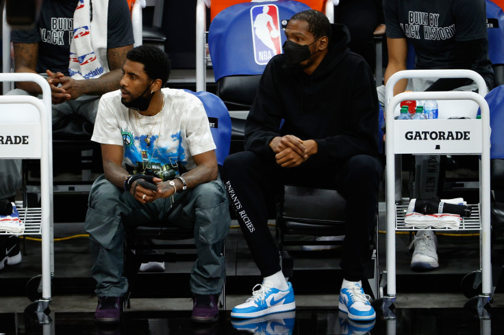 Kyrie Irving #11 and Kevin Durant #7 of the Brooklyn Nets watch from the bench during the first half of the NBA game against the Phoenix Suns at Phoenix Suns Arena on February 16, 2021 in Phoenix, Arizona.