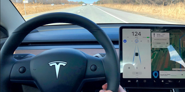 The inside of a Tesla vehicle is viewed as it travels along a highway.