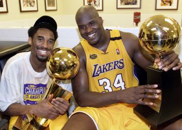 Kobe Bryant (L) of the Los Angeles Lakers holds the Larry O'Brian trophy as teammate Shaquille O'Neal (L) hold the MVP trophy after winning the NBA Championship against Indiana Pacers 19 June, 2000