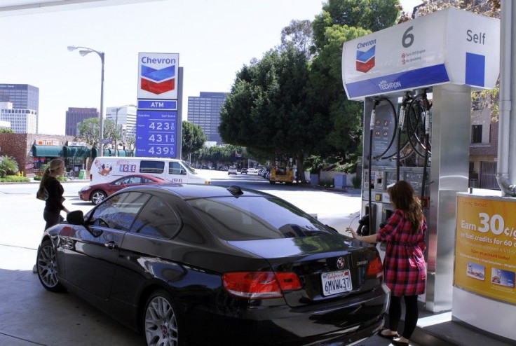 A woman stands at a petrol pump at a Chevron gasoline station in Los Angeles, April 11, 2011.