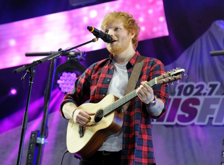 Performing artist Ed Sheeran is pictured playing guitar.