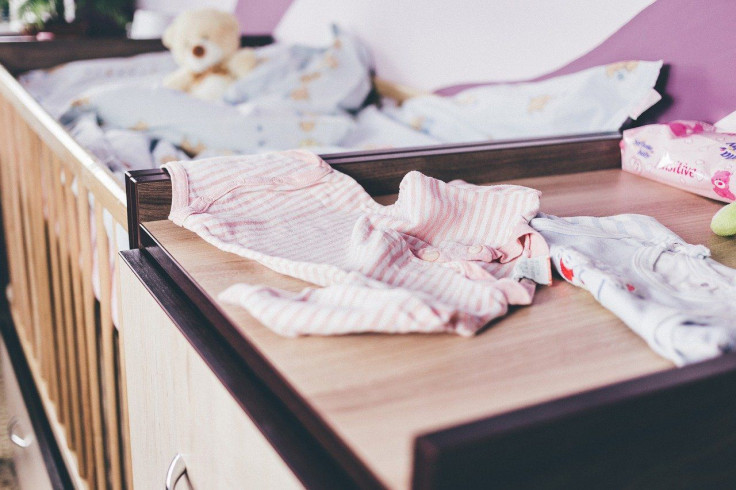 Pictured: Representative image of baby clothing items close to a crib.
