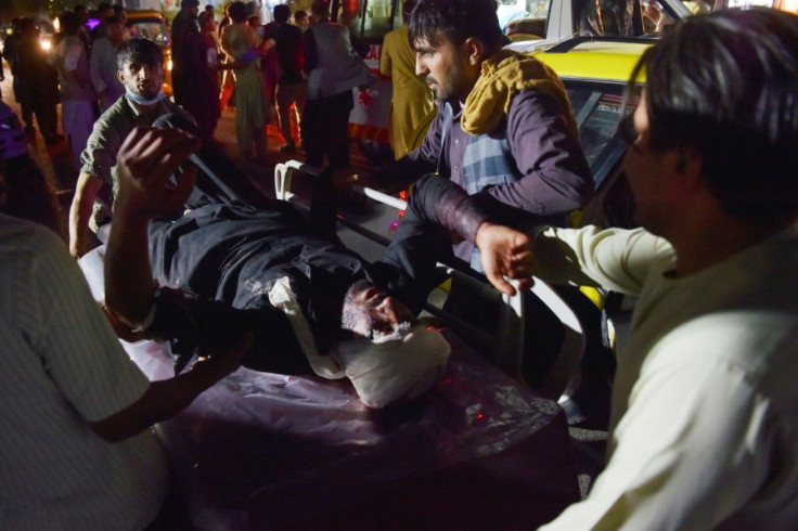 Medical and hospital staff bring an injured man on a stretcher for treatment after two blasts, which killed at least five and wounded a dozen, outside the airport in Kabul