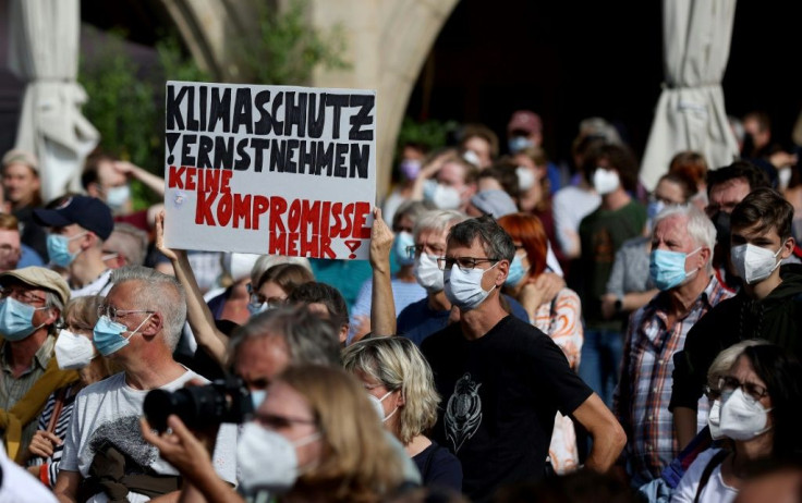 A supporter holds a banner reading 'Take climate change seriously - no more compromise'