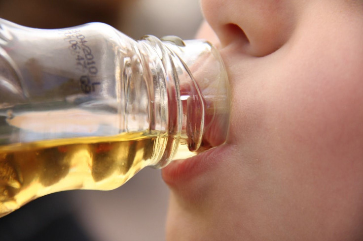 A woman drinks a beverage in this representational image. 