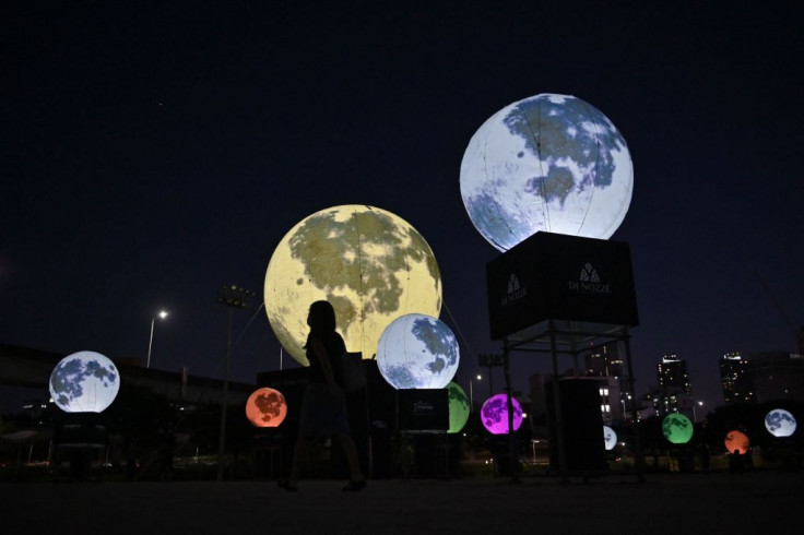 A visitor walks past balloon installations depicting the moon at a riverside park in Seoul on September 18, 2020. - Seoul Seongdong-gu District Office installed a 12-metre-diameter balloon and 20 other smaller balloons covered with an image of the lunar s