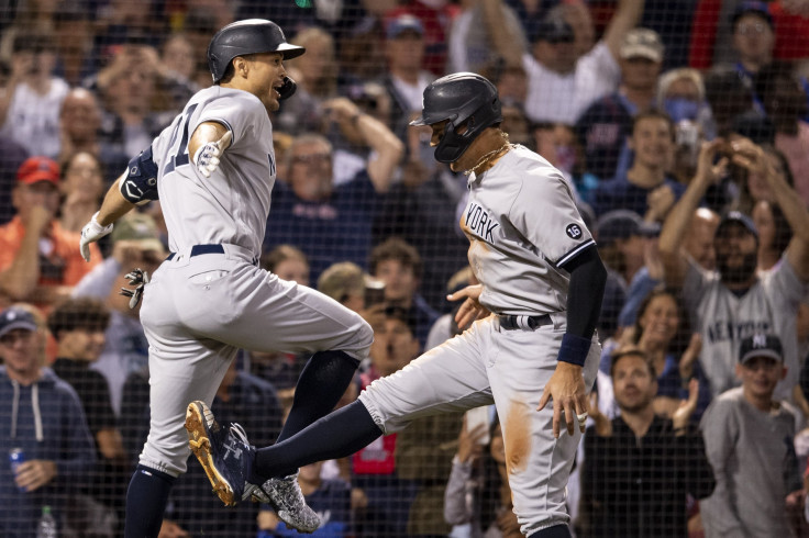Giancarlo Stanton #27 of the New York Yankees reacts with Aaron Judge #99 after hitting a two run home run during the eighth inning of a game against the Boston Red Sox on September 26, 2021 at Fenway Park in Boston, Massachusetts.