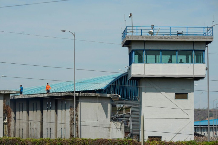 Inmates walk on the roof of a wing of the main regional prison in Guayaquil, Ecuador, where at least 24 prisoners were killed in a gun battle among inmates