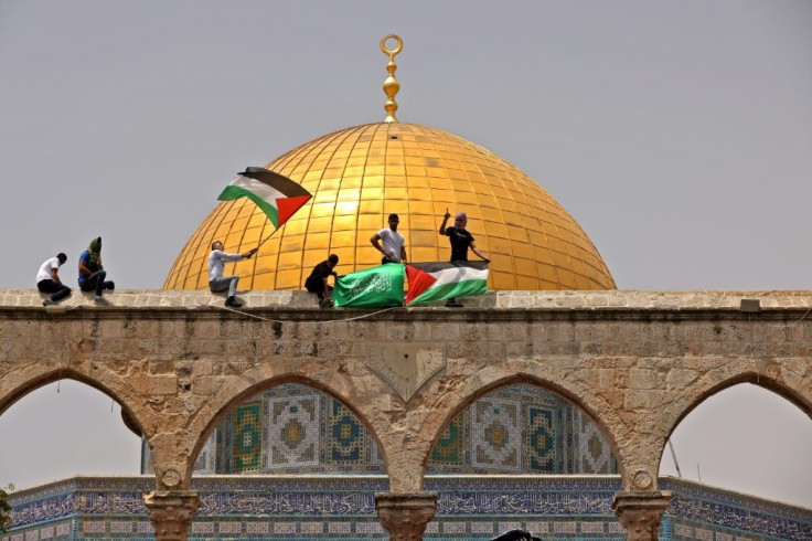 Palestinians wave the Palestinian and Hamas flags during fresh clashes with Israeli security forces in Jerusalem's Al-Aqsa mosque compound on May 21, 2021