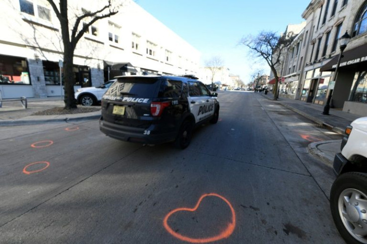 A Waukesha police vehicle drives by evidence markers on the street in downtown Waukesha, Wisconsin on November 22, 2021, after a vehicle drove through a Christmas parade the night before killing five people