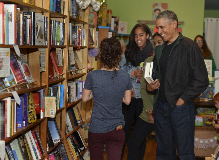 U.S. President Barack Obama and his daughters Malia (center) and Sasha (partly hidden) interact with Upshur Street Books manager Anna Thorn as they buy books from the store in Washington D.C., Nov. 28, 2015.