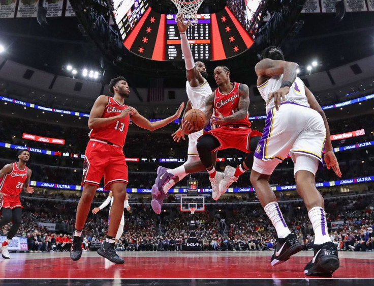 DeMar DeRozan #11 of the Chicago Bulls passes to teammate Tony Bradley #13 under pressure from LeBron James #6 (rear) and DeAndre Jordan #10 of the Los Angeles Lakers