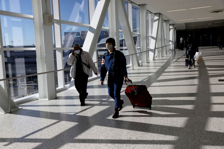 Air travellers wearing protective face masks, amid the coronavirus disease (COVID-19) pandemic, walk at JetBlue Terminal 5 at JFK International airport in New York, U.S., November 16, 2021. 