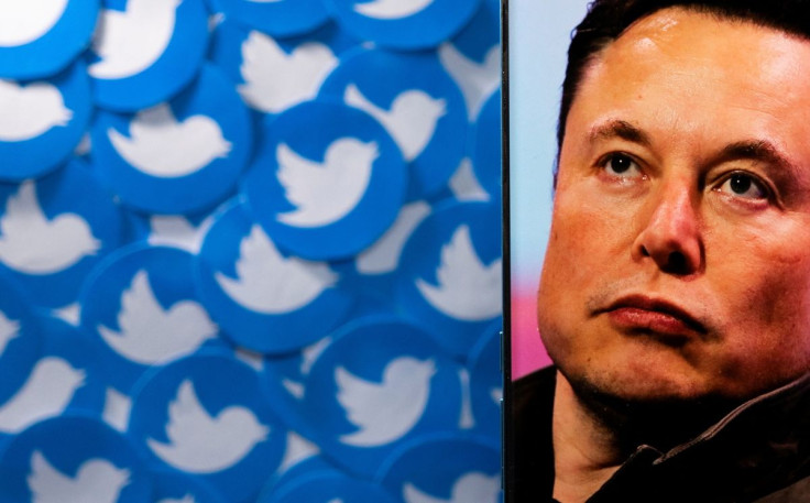 An image of Elon Musk is seen on a smartphone placed on printed Twitter logos in this picture illustration taken April 28, 2022.