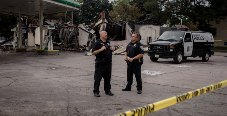 Two police officers stand near the remains of a gas station August 15, 2016 in Milwaukee, Wisconsin, after police in the Midwestern city faced off with protesters August 13 and 14 following the death of 23-year-old Sylville Smith, who officials say was ar