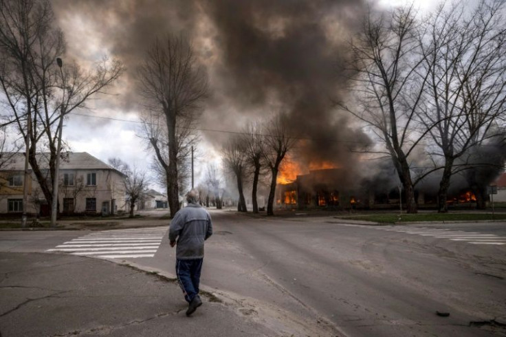 A man walks on a pavement as a house is burning following a shelling Severodonetsk, Donbass region, on April 6, 2022