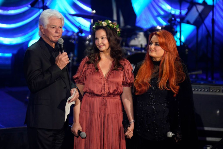 NASHVILLE, TENNESSEE - MAY 15: (L-R) Larry Strickland, Ashley Judd, and Wynonna Judd speak onstage for Naomi Judd: 'A River Of Time' Celebration at Ryman Auditorium on May 15, 2022 in Nashville, Tennessee. 