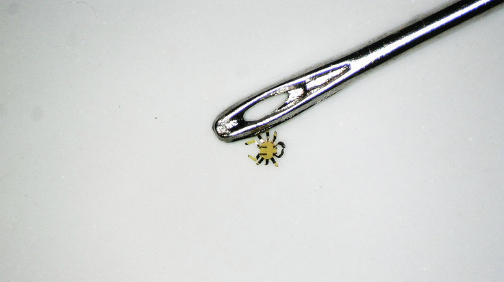 Pictured: Smaller than a flea, tiny robotic crab sits next to the eye of a sewing needle.