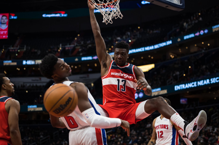 Thomas Bryant #13 of the Washington Wizards hangs on the rim after dunking in front of Hamidou Diallo #6 of the Detroit Pistons during the second half at Capital One Arena on March 1, 2022 in Washington, DC.