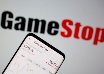 GameStop is laying off people as the company tries to fit in with a digitally-transforming videogame industry. In photo: GameStop stock graph is seen in front of the company's logo in this illustration taken February 2, 2021.