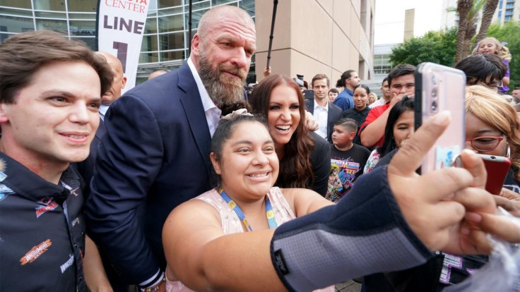 Triple H and Stephanie McMahon pose for a picture with a fan ahead of a WWE show.