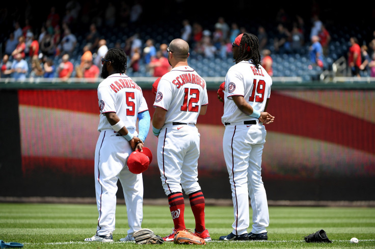 Josh Harrison #5, Kyle Schwarber #12, and Josh Bell #19 of the Washington Nationals stand for the playing of the national anthem prior to the game against the New York Mets at Nationals Park on June 20, 2021 in Washington, DC.