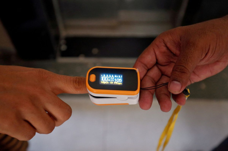 A medical worker (R) puts a pulse oximeter on a woman's finger to check her oxygen level during a door-to-door survey for the coronavirus disease (COVID-19) amidst its spread in Ahmedabad, India June 26, 2020.