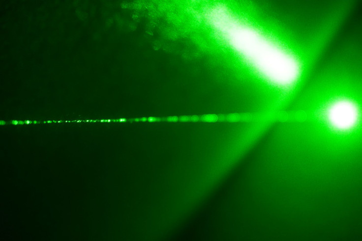 A green laser shot through a cloud of suspended particles.