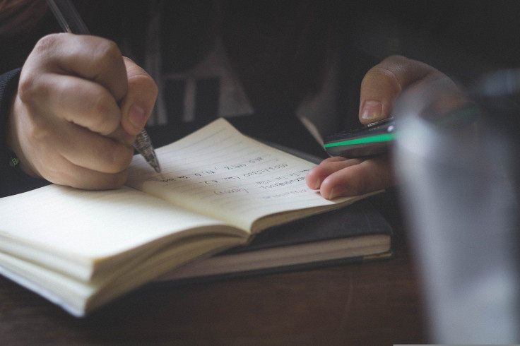 Representation. A student writing on a notebook.