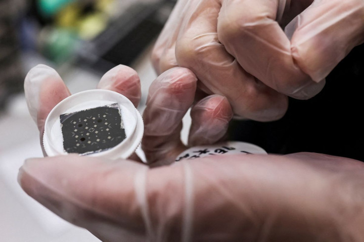 An engineer holds a chip while posing for a photo, he is in the middle of testing reactions from different materials and shapes that can have on the chip at the Taiwan Semiconductor Research Institute (TSRI) in Hsinchu, Taiwan, February 11, 2022.