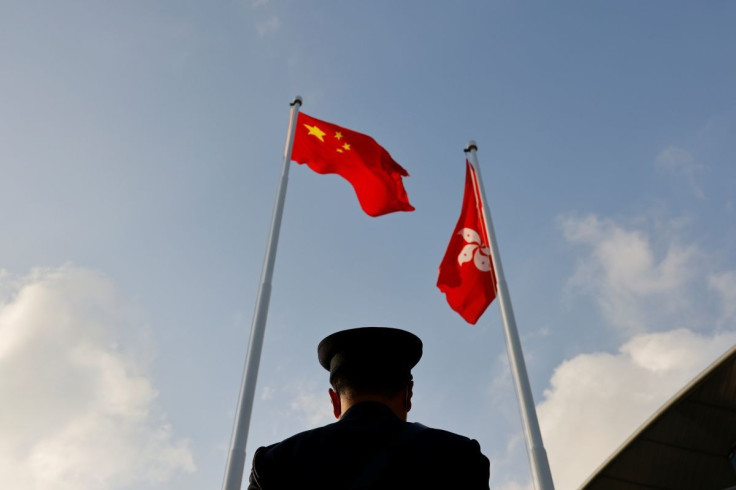 A police officer stands guard below China and Hong Kong flags during a flag raising ceremony, a week ahead of the Legislative Council election in Hong Kong, China, December 12, 2021.