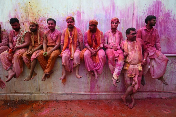 Hindu devotees sit in the columns of a temple as they take a break from participating in Holi celebrations