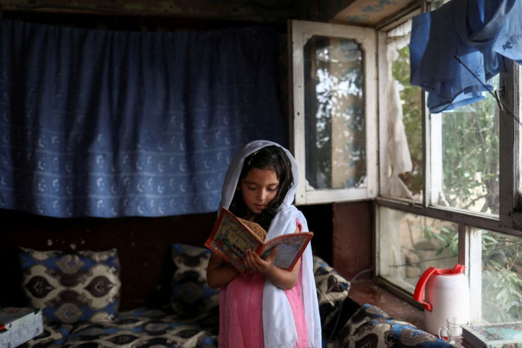 FILE PHOTO - An Afghan girl reads a book inside her home in Kabul, Afghanistan, June 13, 2022.