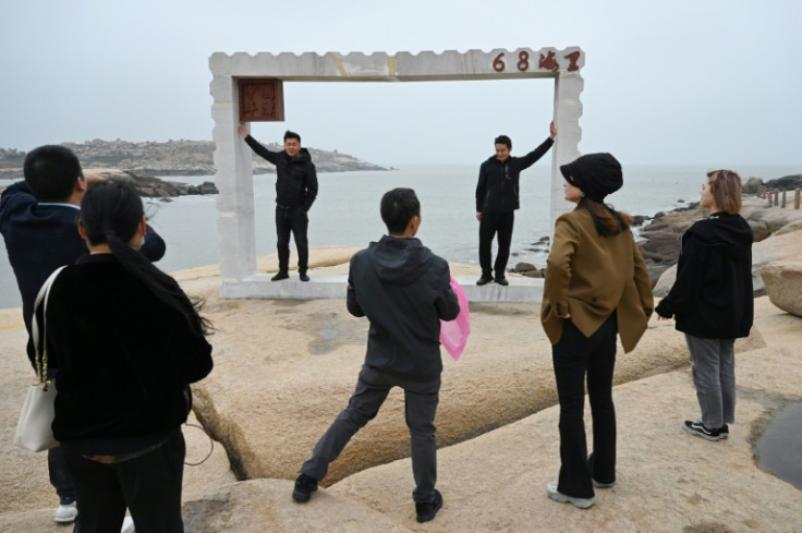 Chinese tourists pose for photos in front of the Taiwan Strait on the coast of Pingtan Island