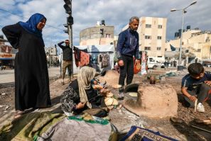 A woman bakes bread outside at a makeshift camp for displaced Palestinians in Rafah, in southern Gaza