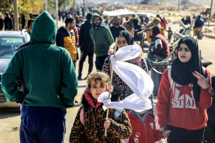 A girl holds a make-shift white flag as she walks with other displaced Palestinians fleeing Khan Yunis in the southern Gaza Strip