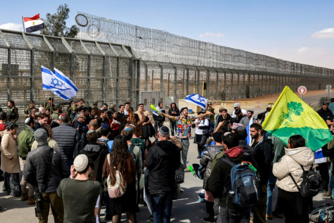 Israeli demonstrators gather by the border fence with Egypt as they attempt to block humanitarian aid trucks from entering Israel on their way to the Gaza Strip