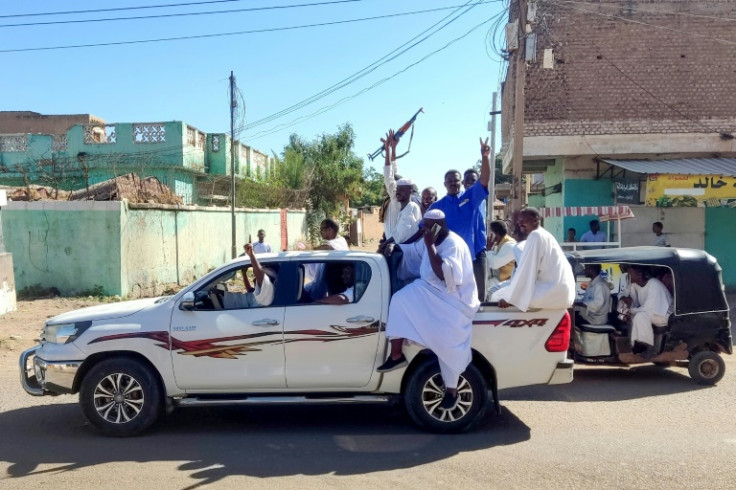 Armed Sudanese civilians wave weapons and chant slogans in Gedaref city, eastern Sudan, on January 1, 2024 to express support for the army