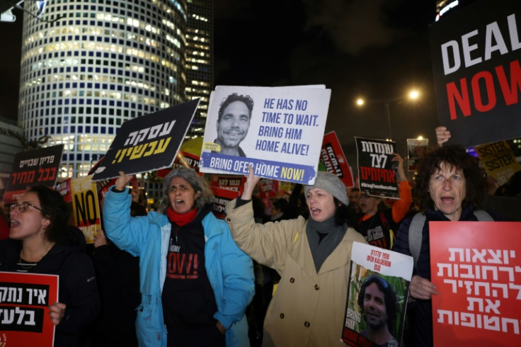 Israeli women raise placards bearing messages and pictures of Israeli hostages held by Hamas since October 7, 2023, as they protest outside the ministry of defence, calling for their release and negotiations for a deal between Israel and Hamas