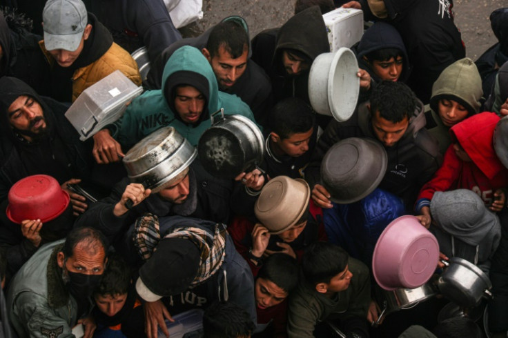 Palestinians receive food rations at a donation point at a camp for displaced people in Rafah